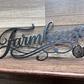 Metal 'Farmhouse' sign on a wooden background